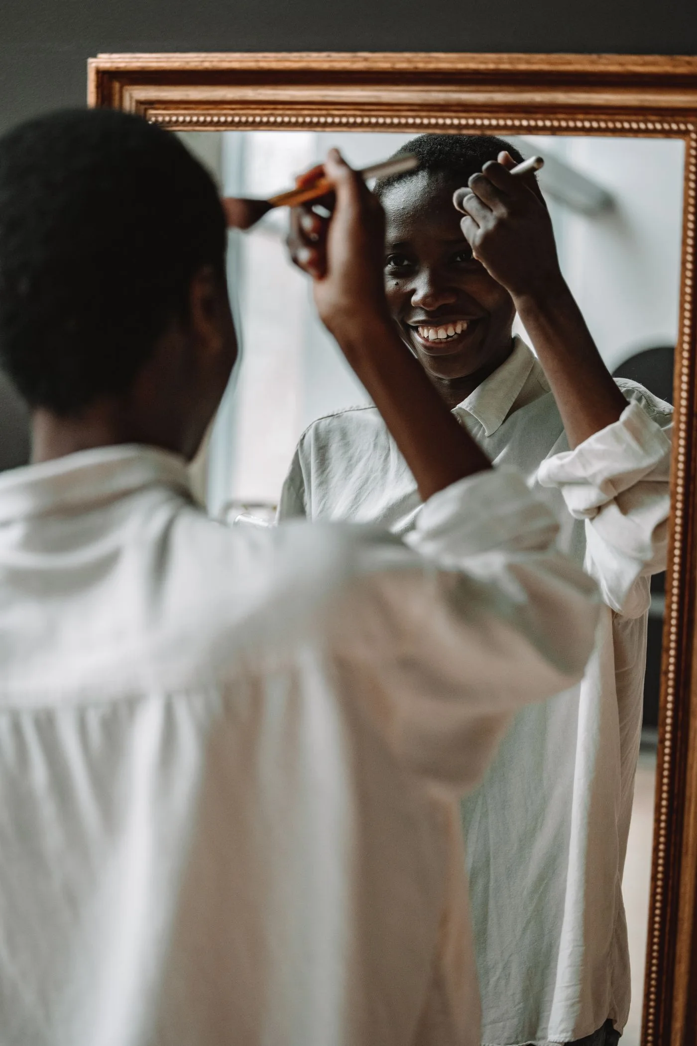 A woman applying makeup while looking into a mirror.