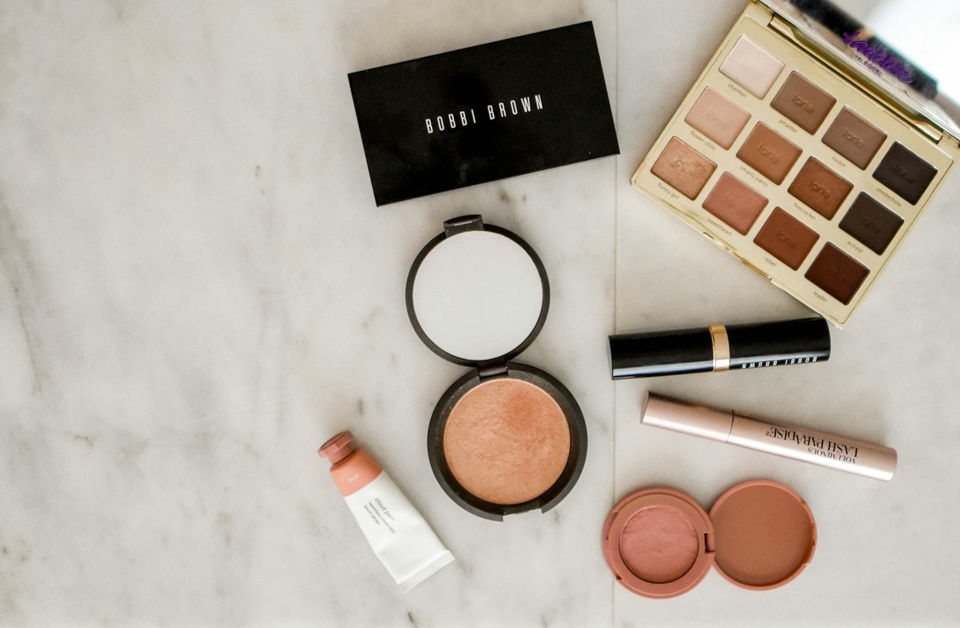 Makeup palette, compact and brushes arranged on a dressing surface