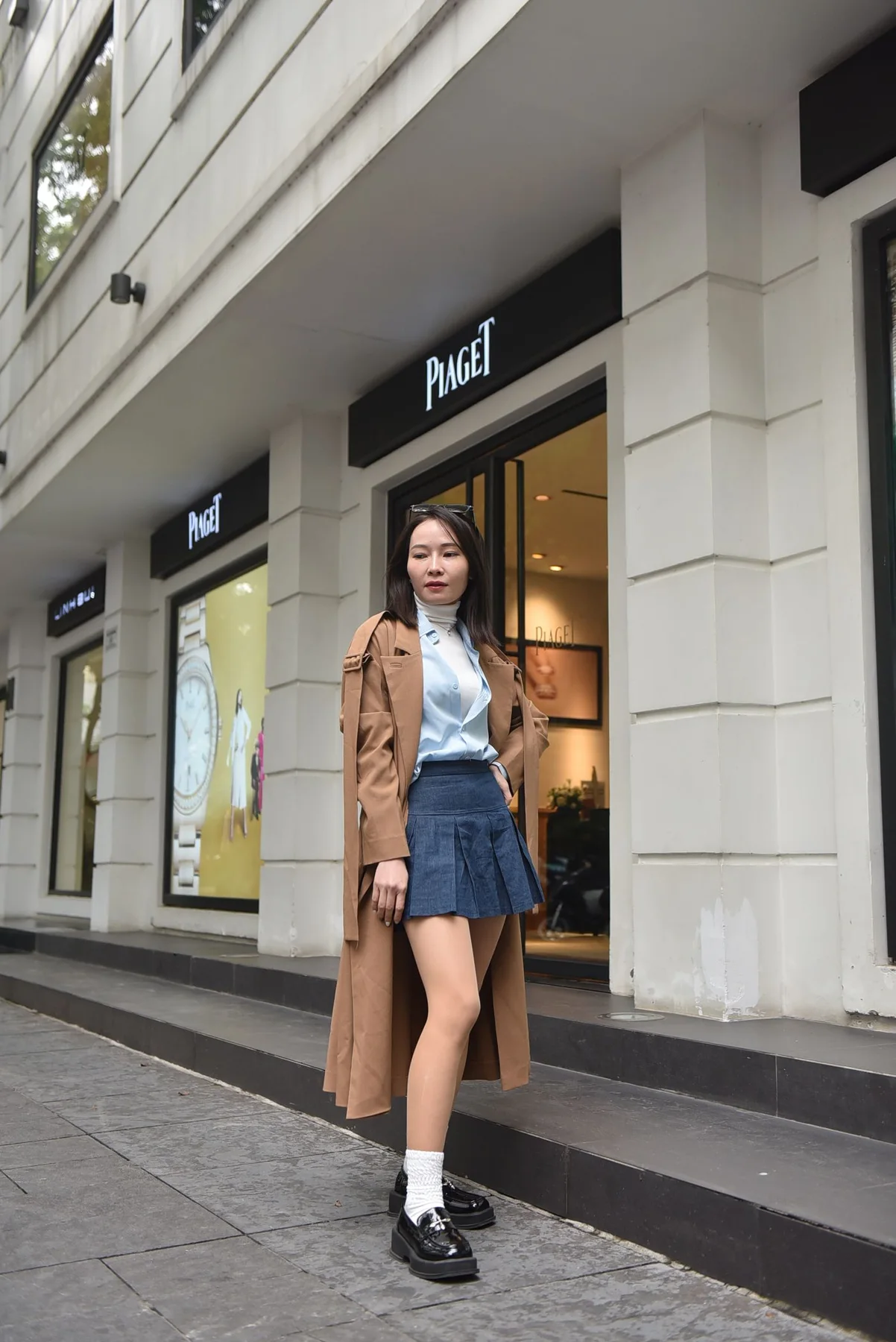 A woman in a wool coat and pleated skirt on a city street.