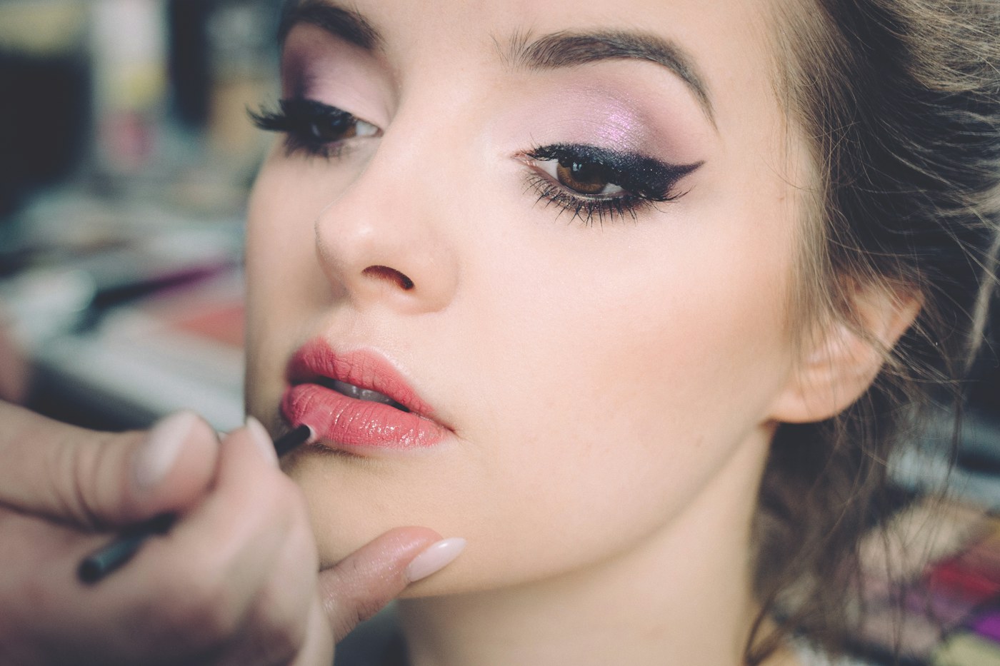 A person applying lip colour to a woman with a small brush.