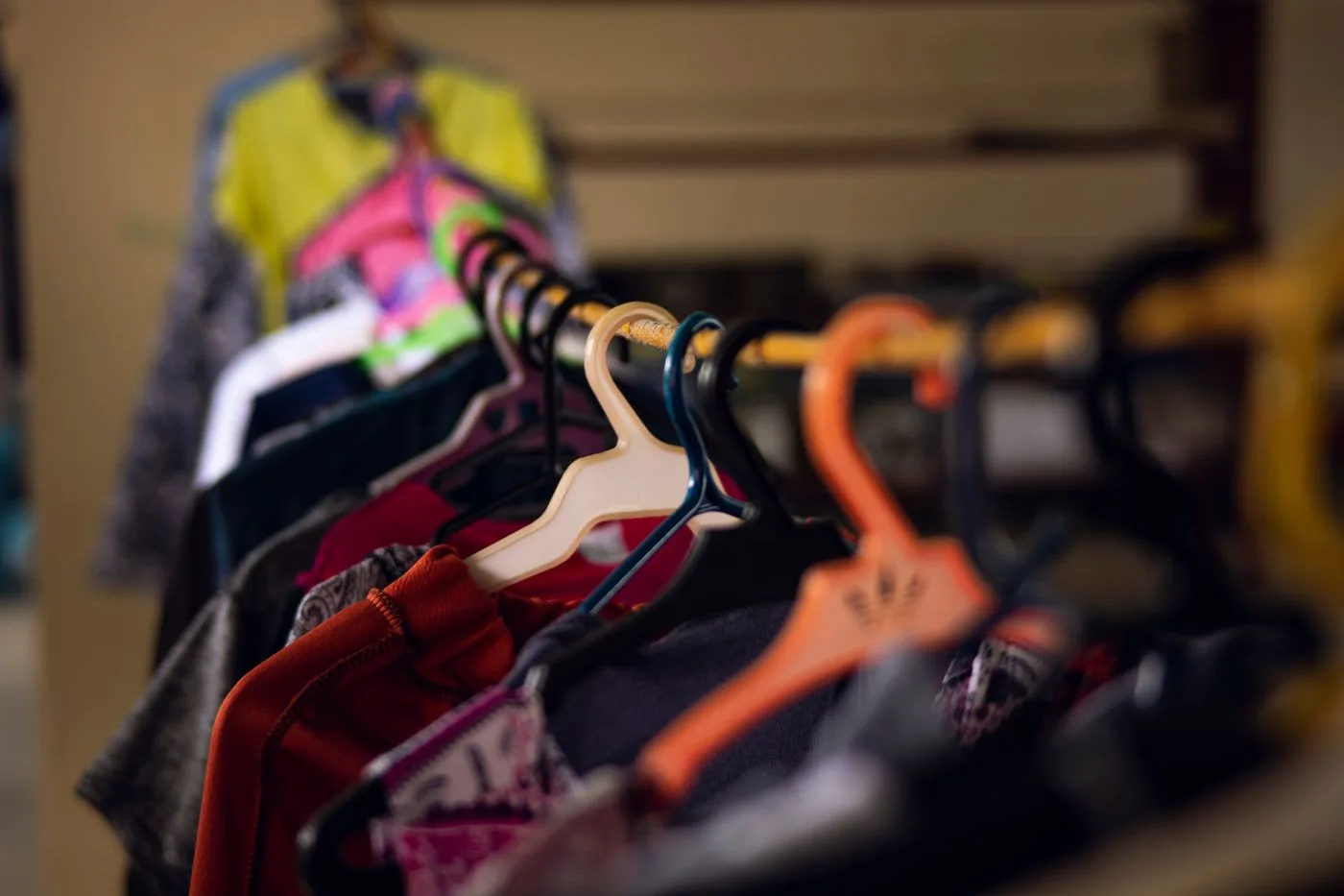 Colourful clothes on hangers along a shop rail.