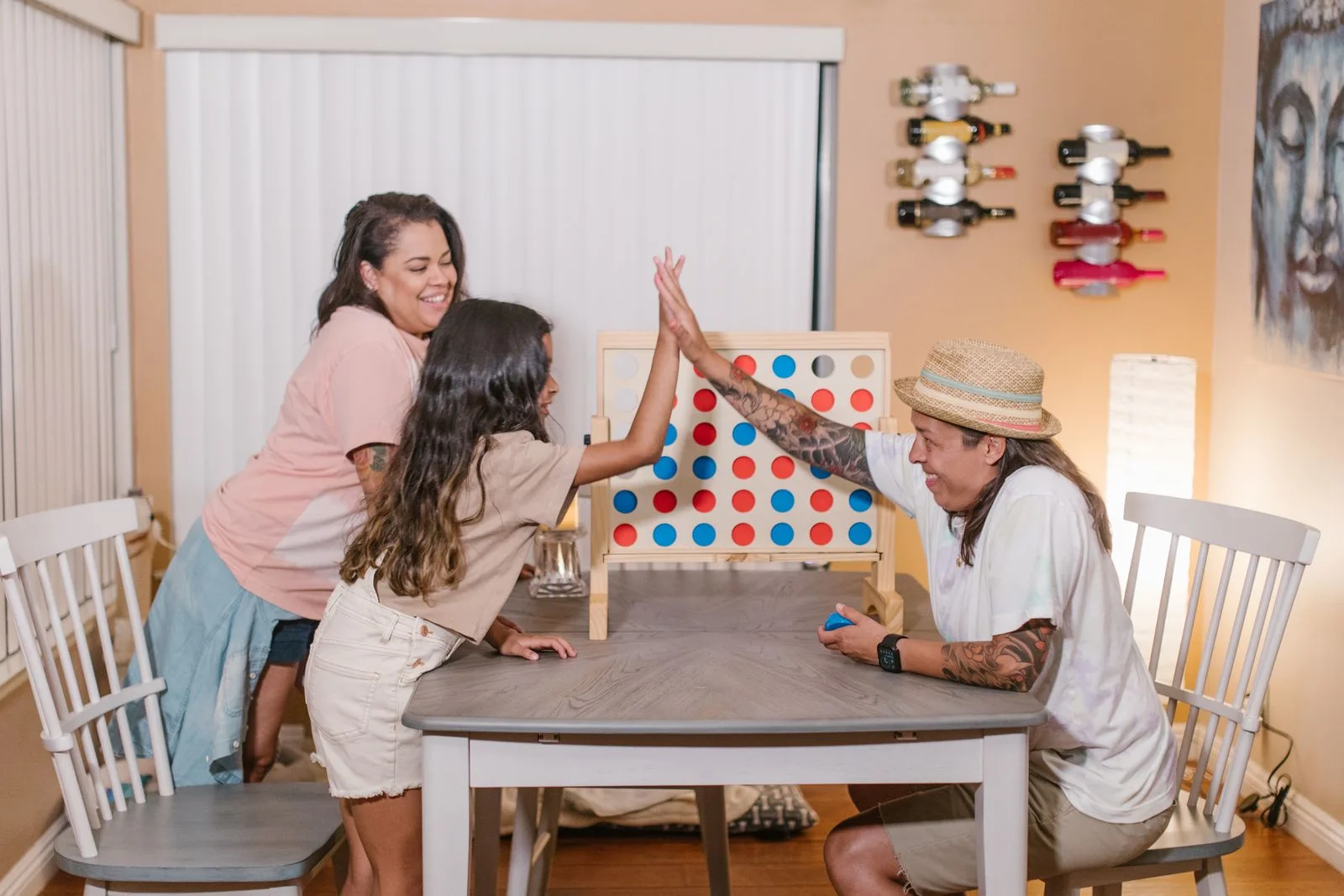 Three people gathered around an upright colourful game board on a table.