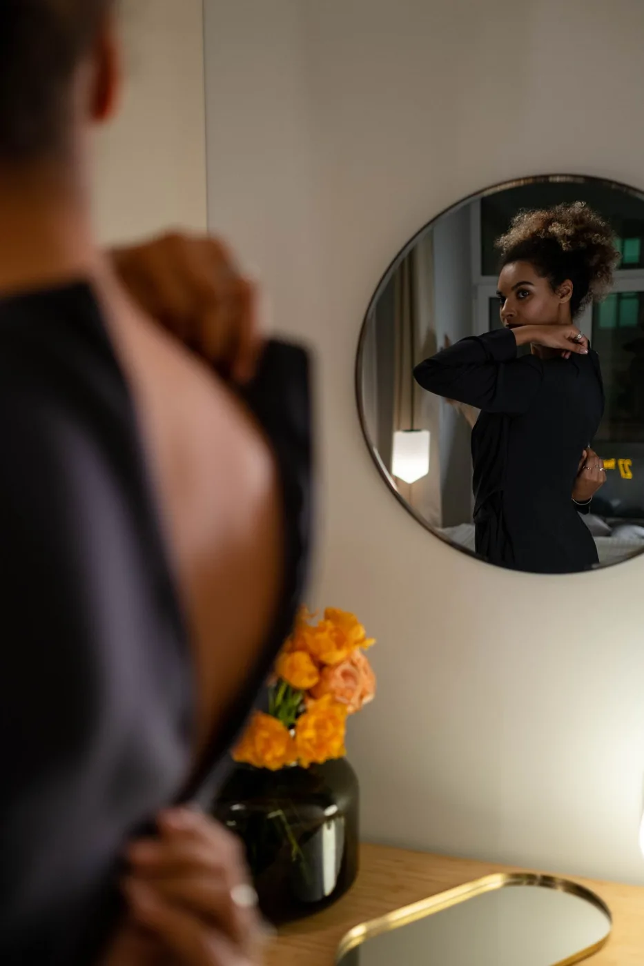 A person checking an outfit in a round wall mirror.