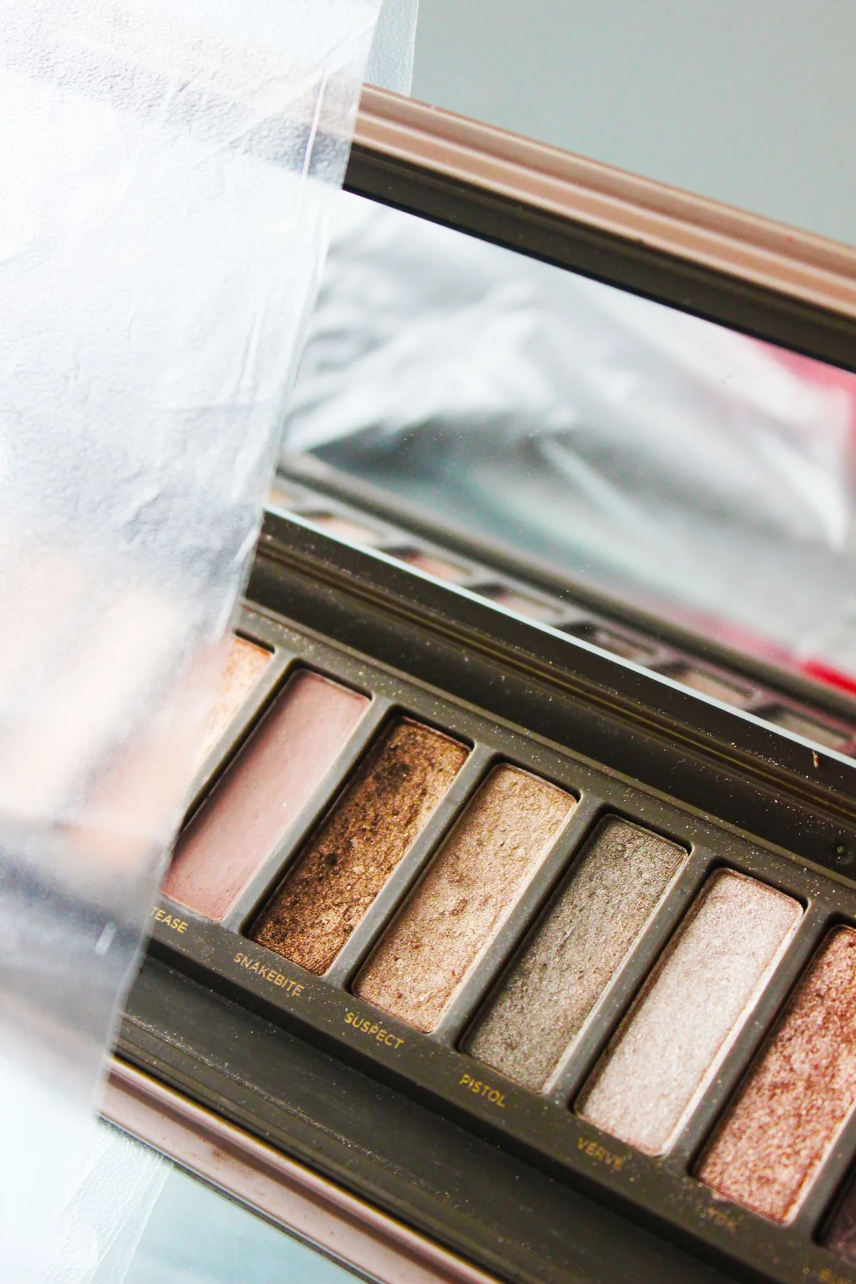 A makeup palette with several shades and a mirror reflection.