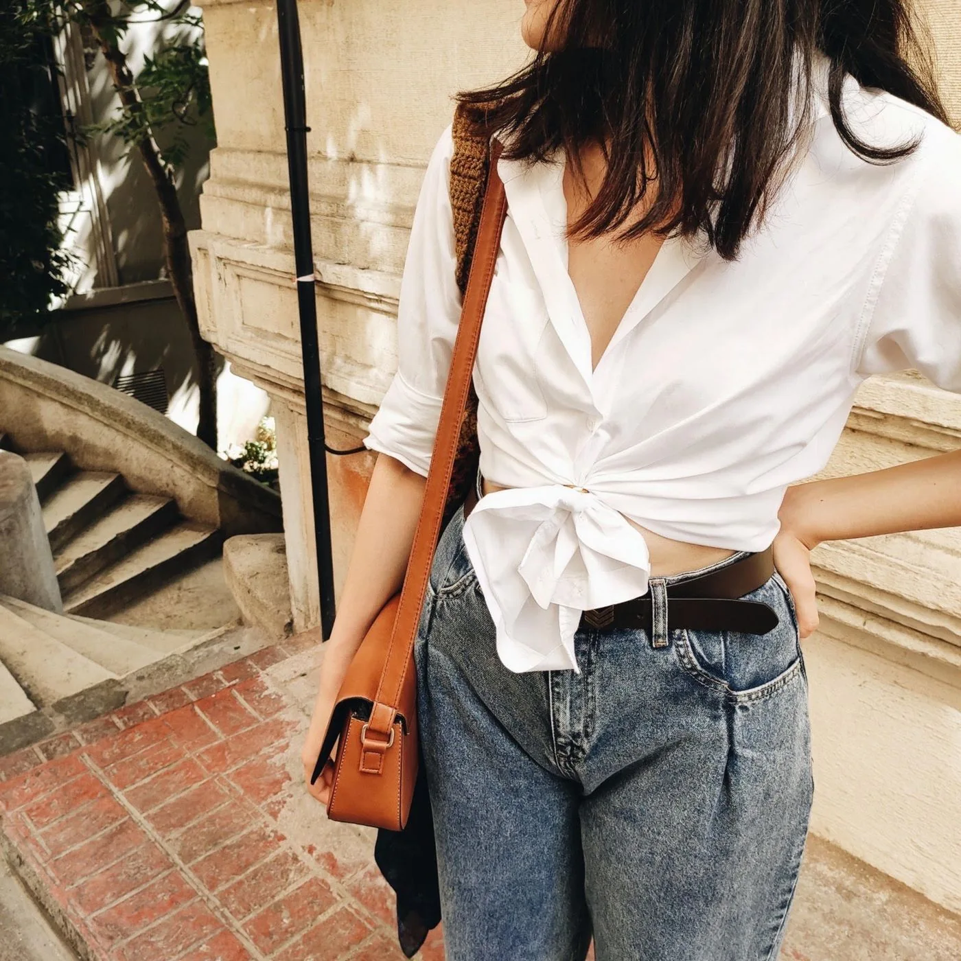 Woman wearing a white blouse and jeans on city steps