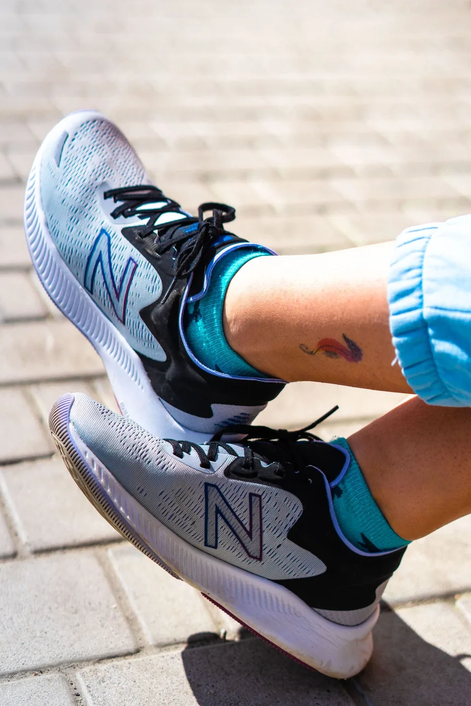 Grey sneakers worn with colourful socks outdoors.
